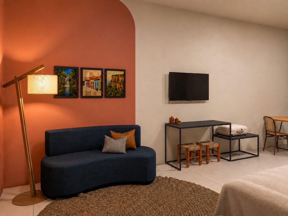 Sala de estar da Hospedaria Terra da Opala, com sofá azul-marinho, parede terracota e iluminação aconchegante