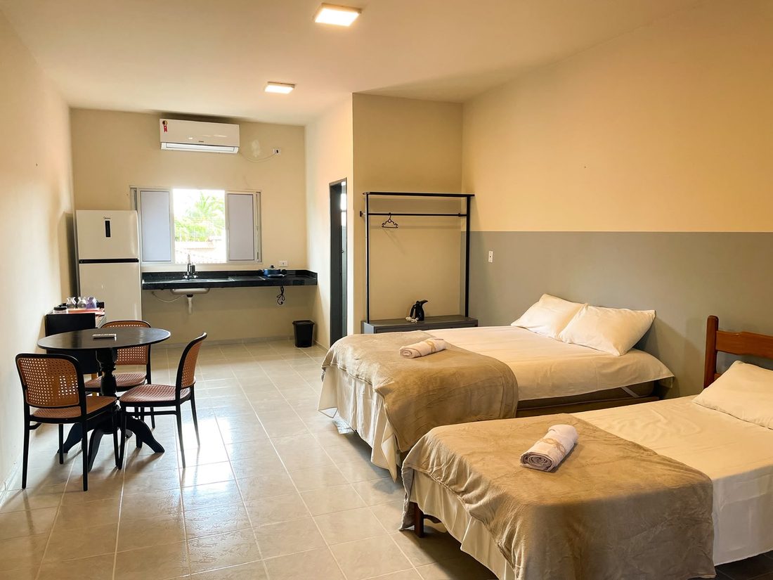 Suíte ampla com duas camas, mesa, ar-condicionado e cozinha compacta